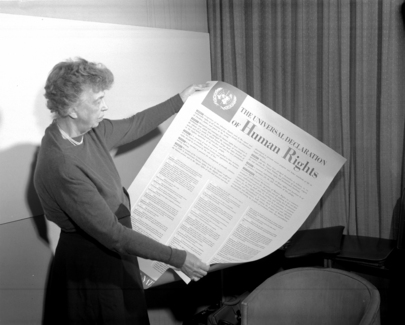 Black-and-white photo of Eleanor Roosevelt with a poster in hand, on which is written the text of the Universal Declaration of Human Rights.