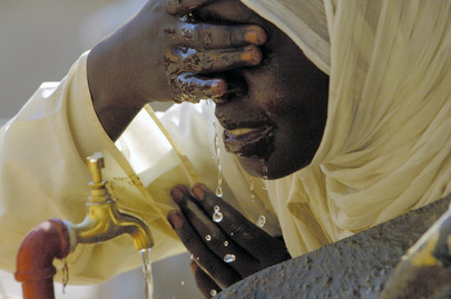 A Sudanese student drinks and washes her face at a new water fountain in a primary school for girls
