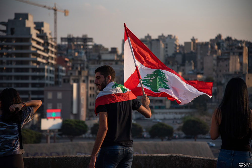 Man during Beirut protests with a flag from Lebanon