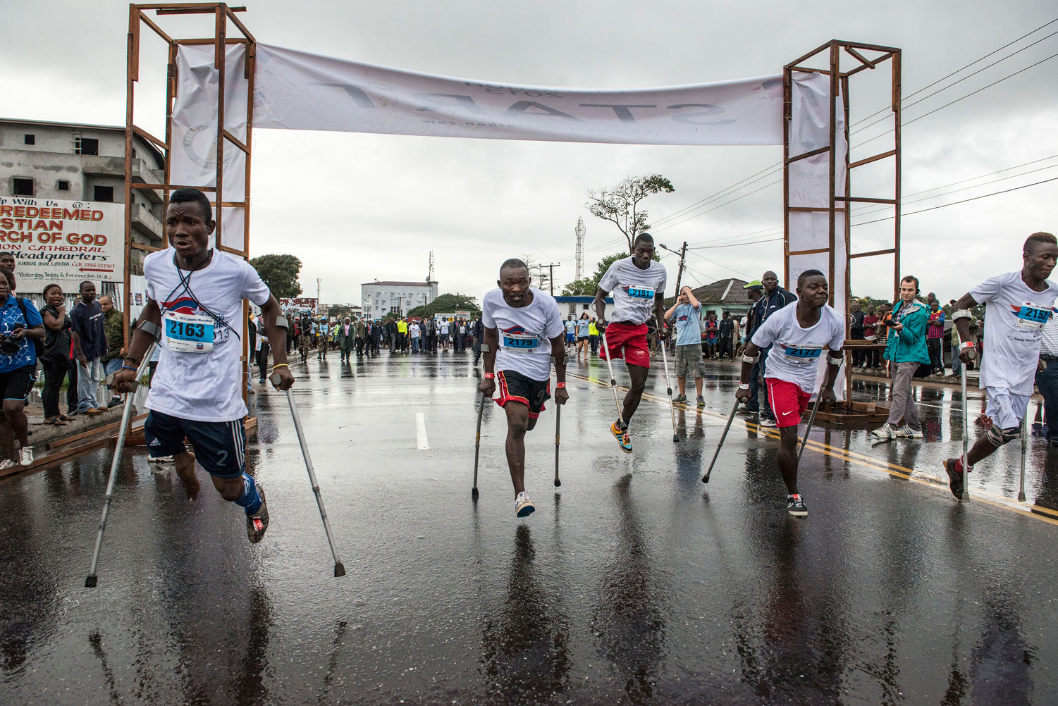 Atleti disabili si spingono in avanti alla partenza della Maratona in Liberia per persone con disabilità. 