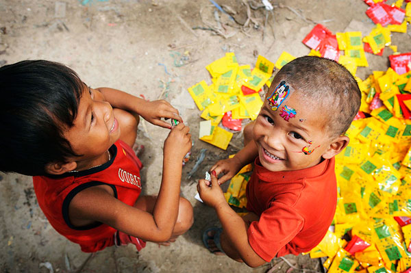 Due bambini giocano con l'immondizia e con adesivi colorati