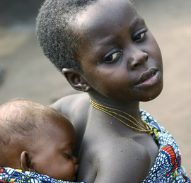 Una bambina porta in spalla un neonato in un villaggio della Repubblica Democratica del Congo