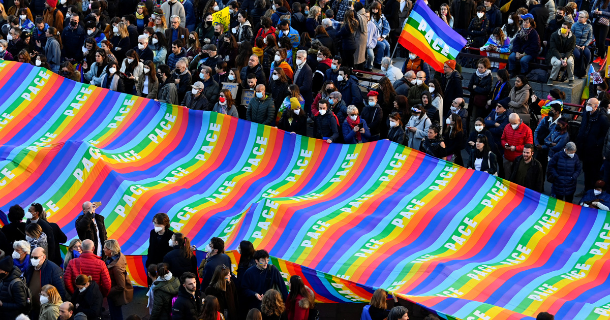 Foto del corteo per Manifestazione per la pace a Milano, la folla porta un'enorme bandiera della pace