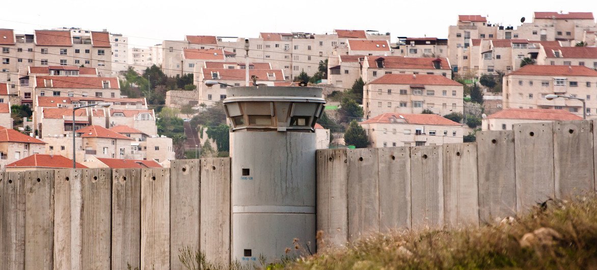 Il Muro di Separazione nei Territori Palestinesi Occupati e dietro di esso un insediamento israeliano