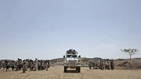 Una jeep bianca dei peacekeepers ONU transita tra due gruppi di persone a Kafod, Sudan