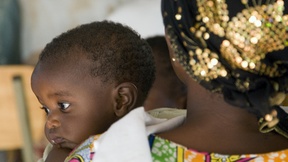 Una donna tiene in braccio un bambino all'interno di un centro di accoglienza per vittime di stupro e violenze durante il genocidio in Rwanda.