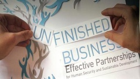 Poster della 59esima Conferenza annuale delle ONG e delle organizzazioni di società civile alle Nazioni Unite. Due mani sistemano su un cartellone delle scritte su carta, componendo il titolo della conferenza