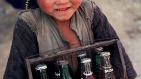 Primo piano di un bambino nepalese che vende delle bibite.