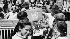 Gli osservatori ONU con la bandiera delle Nazioni Unite insieme ad un gruppo di bambini in Palestina, 1948.