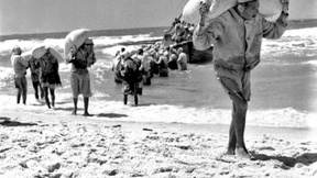 Su una spiaggia vicino a Gaza, rifugiati scaricano sacchi di farina trasportati a Gaza dall'Agenzia delle Nazioni Unite per il Soccorso e l'Occupazione dei Profughi (UNRWA), maggio 1957.