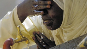 A Sudanese student drinks and washes her face at a new water fountain in a primary school for girls