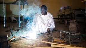 Persona con disabilità del Nord Darfur con una mutilazione alle gambe che costruisce una stampella in un laboratorio di una organizzazione locale.