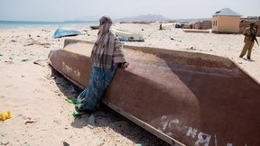 Una donna etiope in piedi accanto ad una barca abbandonata sulla spiaggia a Bossaso, uno dei porti più grandi della Somalia, 2011