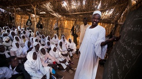Un insegnante e i suoi studenti durante la lezione in aula nel campo per sfollati di Nifasha (Nord Darfur).