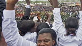 Una donna esulta durante la cerimonia per l'indipendenza del Sud Sudan, dietro di lei altre persone con le mani alzate e sullo sfondo le sfilate della cerimonia.