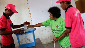 Two Polling officers aid a voter cast her ballot in Timore-Leste’s parliamentary elections