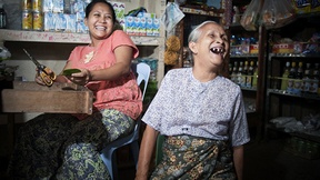 Una donna di settant'anni ride insieme con un altro membro della famiglia dentro un negozio a Tachilek, Myanmar