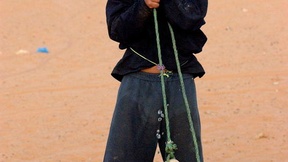 A child from Dakhla Refugee Camp, Algeria, gets his fill of water from a well. (23 June 2003)