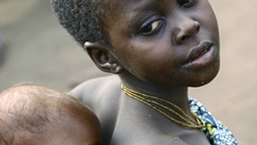 Una bambina porta in spalla un neonato in un villaggio della Repubblica Democratica del Congo