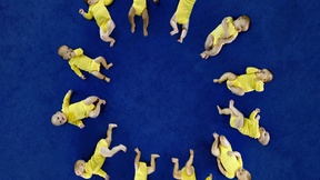 sfondo blu, neonati vestiti di giallo disposti in cerchio