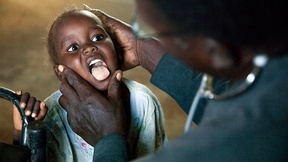 Foto di bambino esaminato dal dottore al fine di valutare se è in grado di viaggiare, Campo per sfollati Kalma di Nyala (Darfur)