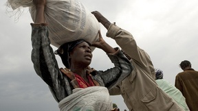 A woman resident of the Kibati camp of the Internally Displaced Persons (IDPs) carries a bag of food ration distributed by the World Food Programme in collaboration with the non-governmental organization, CARITAS.