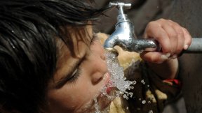 Un bambino che beve acqua da un rubinetto