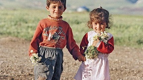 Bambini iracheni in un campo di sfollati interni con dei fiori in mano, Iraq, 1997