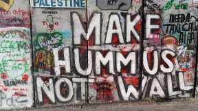 Scritta "Make hummus not wall" che si trova sul muro di divisione tra Israele e Palestina