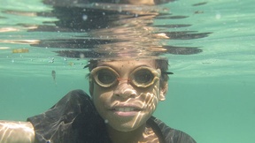 Un bambino che pesca con occhialini di legno nelle acque dell'isola di Atauro, Timor-Leste