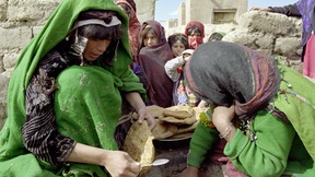 Donne afgane preparano un pasto sotto gli occhi dei propri bambini all'interno del campo profughi di Maslakh