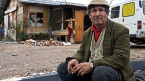 Uomo appartenente all'etnia Rom seduto davanti ad un alloggio fatiscente. Foto scattata durante la visita del Commissario Hammarberg (CoE) nel 2009.