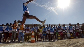 Spettatori guardano un giovane haitiano levarsi in volo per il suo salto in lungo