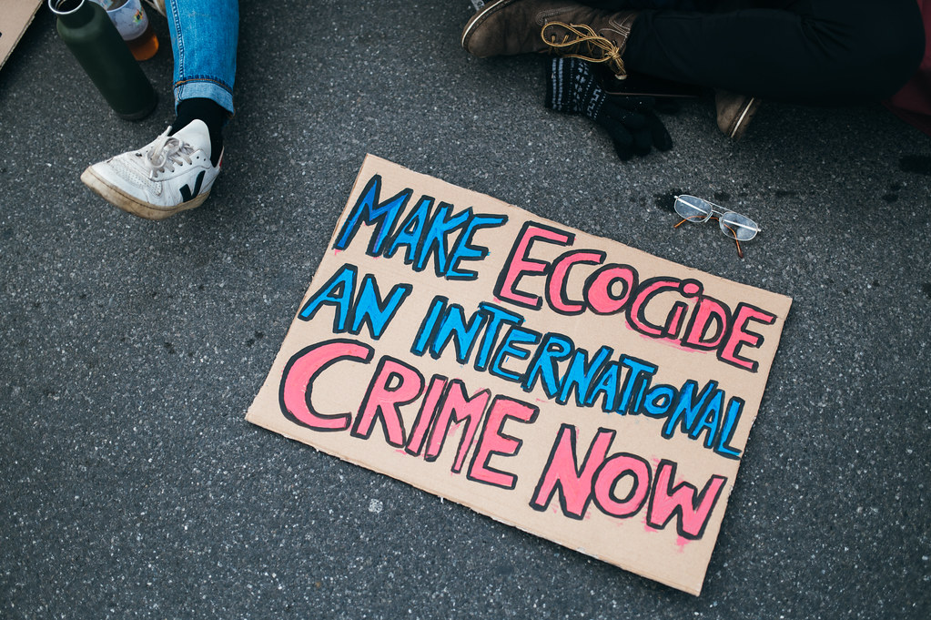 "Make Ecocide An International Crime Now" sign on the tarmac at a rally against climate change