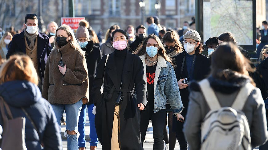 crowded_street_with_some_people_wearing_masks