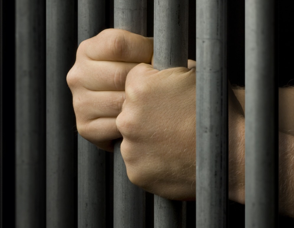 Mani che escono dalle sbarre di un carcere