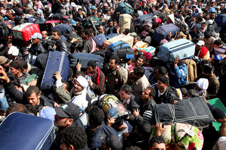 Foto di migliaia di persone con pacchi e valigie tentano di lasciare la Libia al confine con la Tunisia