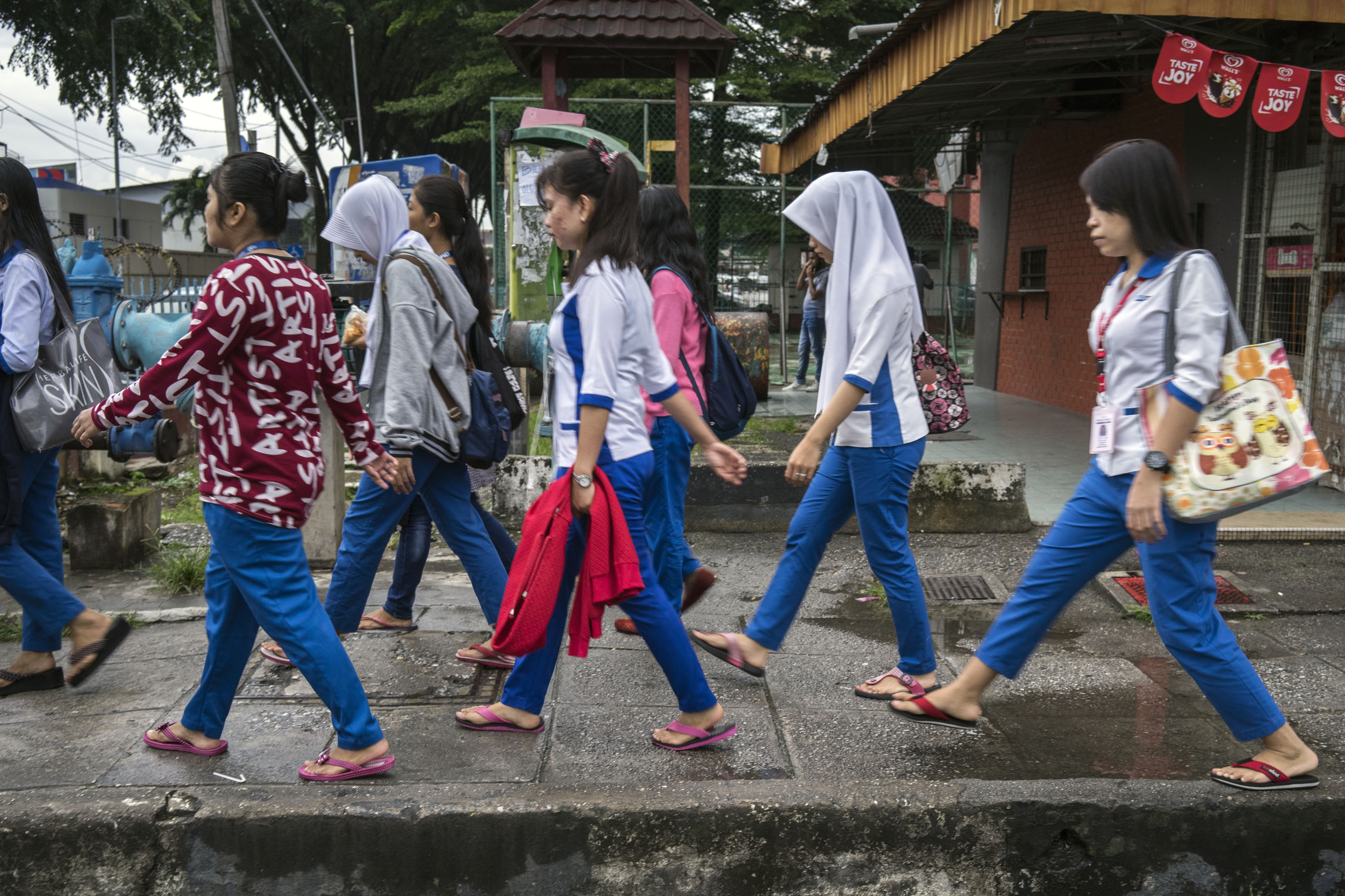 A group of young women migrant workers make their way through a labyrinth of back alleys to get to work at a nearby hi-tech factory facility where they are employed from 7pm-7am daily, in Petaling Jaya, Malaysia, Tuesday 28 November, 2017.